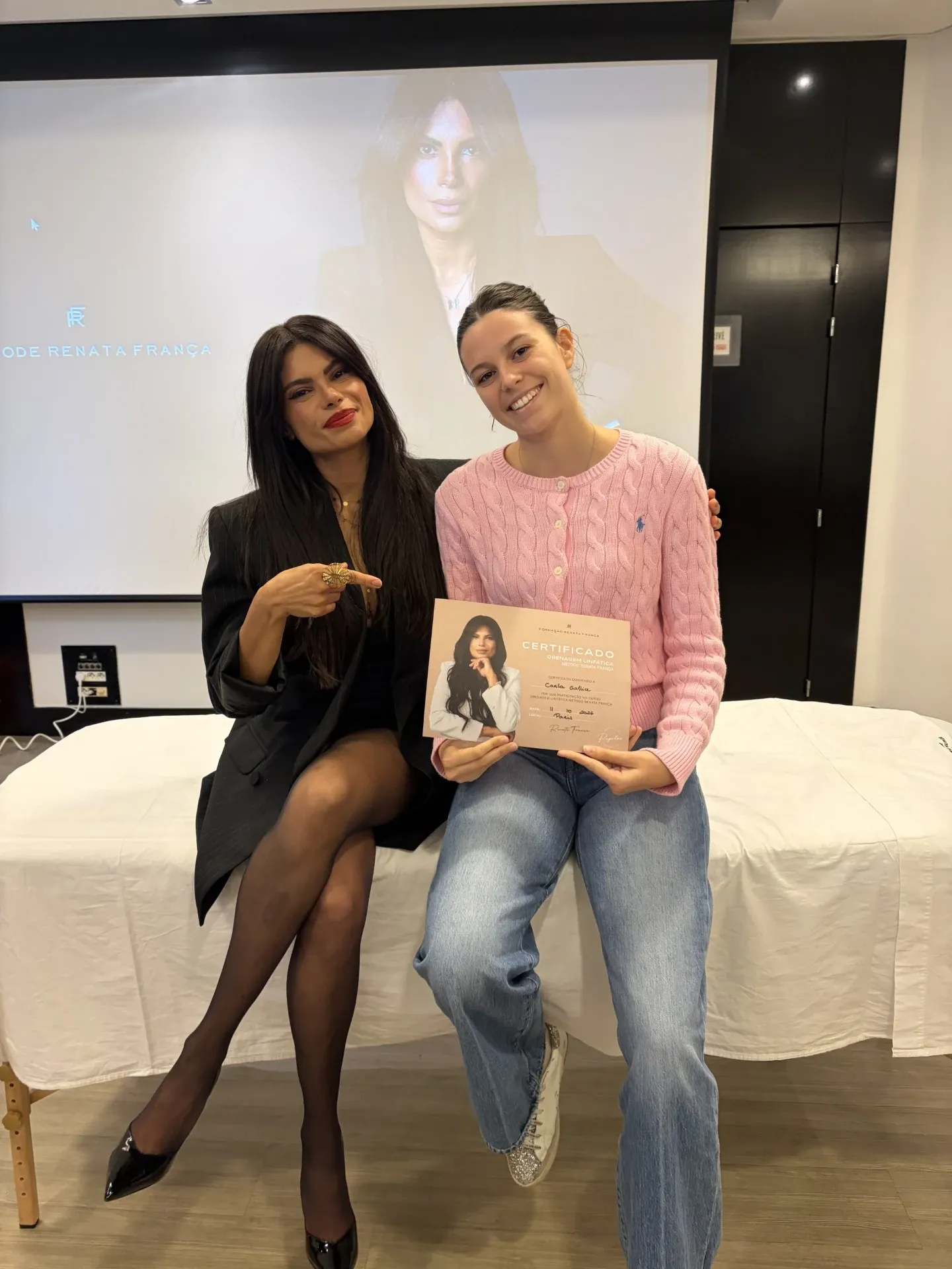 Carla, son certificat de drainage lymphatique méthode Renata França en main, assise à côté de Renata França.