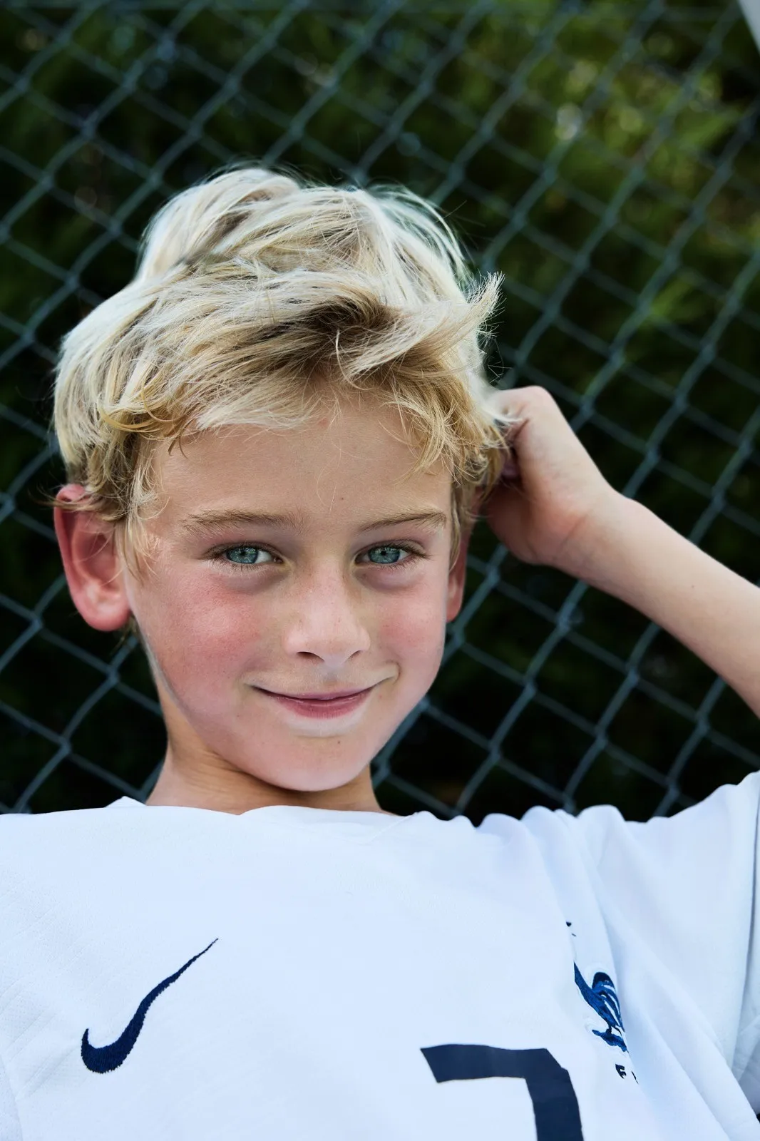 Un jeune garçon blond en maillot de football, souriant.