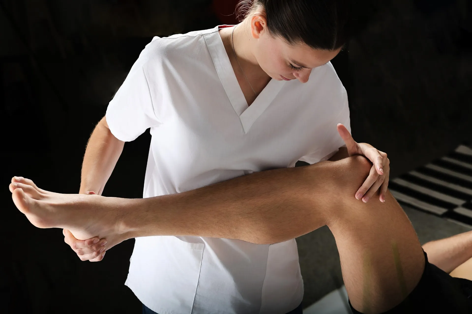 Carla Gallice mobilise le genou d’un patient allongé.